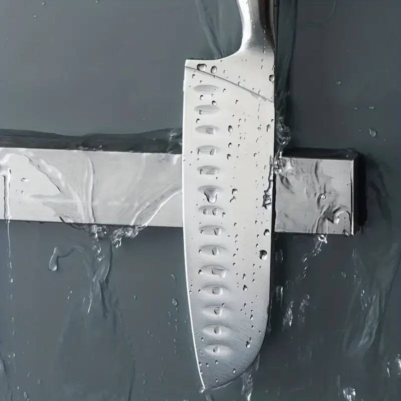 Stainless steel wall-mounted magnetic knife holder by Maison Verdane holding kitchen knives in a modern kitchen setting.