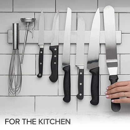 Stainless steel magnetic knife holder mounted on kitchen wall, holding various knives securely for easy access.